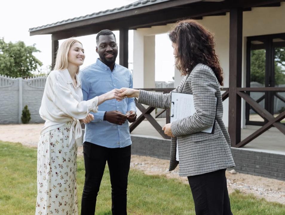 An agent handing keys to happy new homeowners